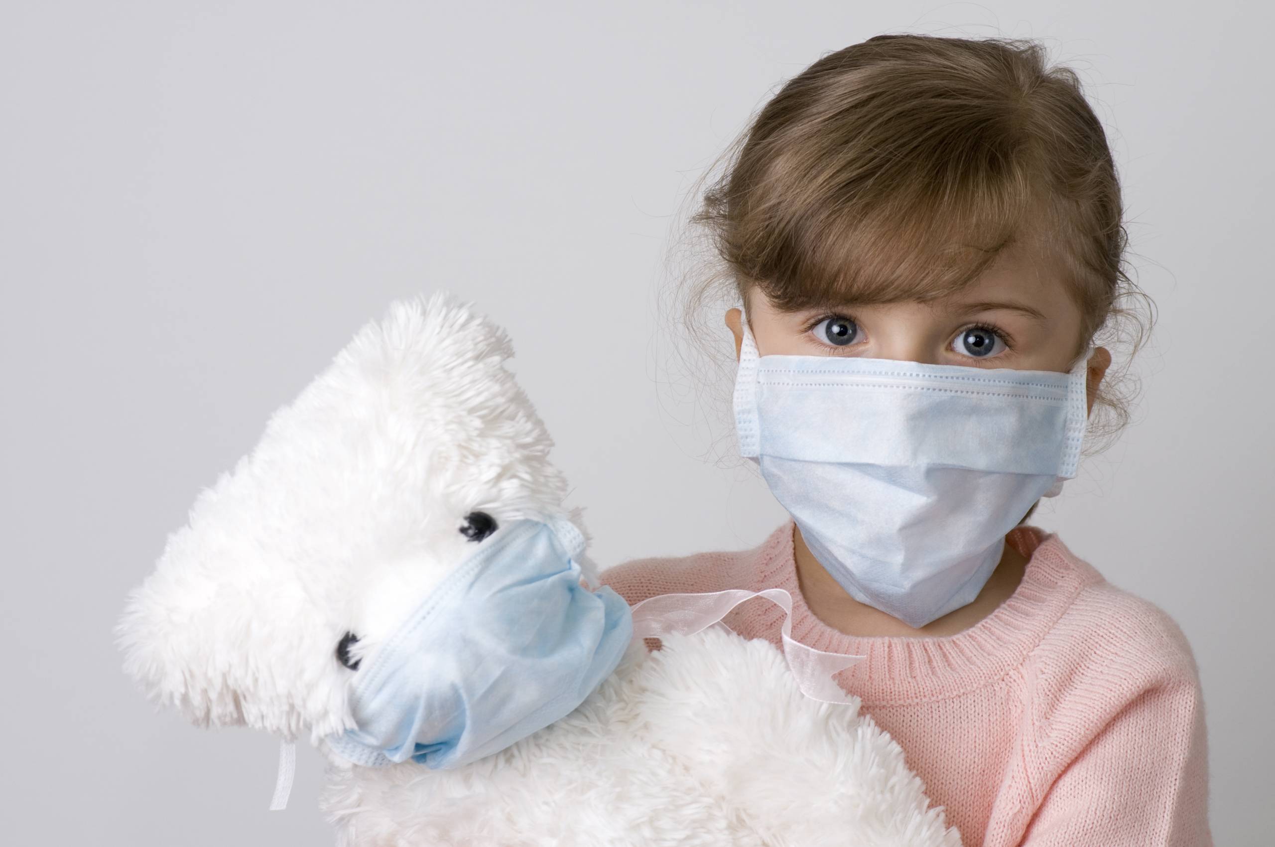 Little girl with teddy bear wearing a protective mask