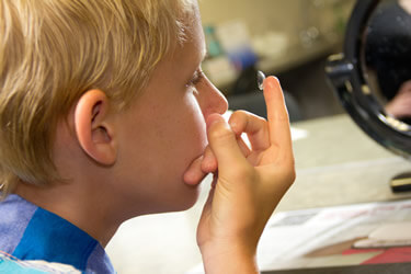 Мальчик одевает линзы